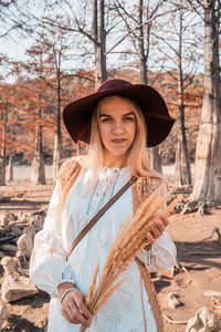 Portrait of young woman standing against bare tree