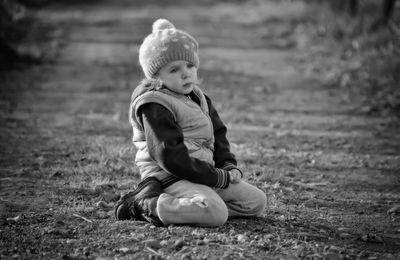 Full length of cute boy sitting on land