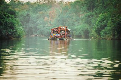 Boat sailing on river against trees