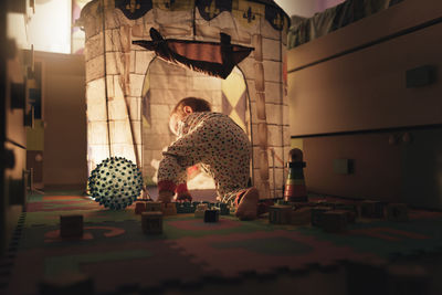 Boy playing by illuminated castle in room at home