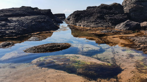 Rock formation on beach against sky