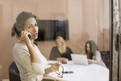 Businesswoman using mobile phone while looking away in creative office