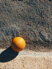 Ridged yellow ball in morning light on concrete