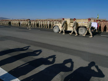 Army soldiers with coffin on road against sky