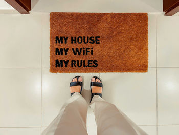 Woman standing by the my house, my wifi, my rules door mat