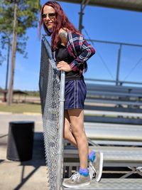 Portrait of young woman standing by railing on bleachers 