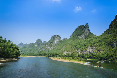 Scenic view of river and mountains against clear blue sky