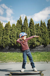 Full length of boy posing while standing on skateboard at yard