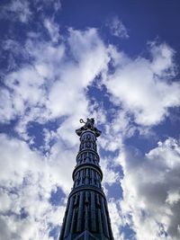 Low angle view of statue of tower against cloudy sky