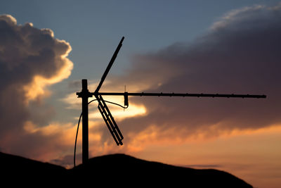 Low angle view of silhouette cranes against sky during sunset