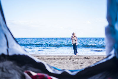 Portrait of woman standing at beach against sky