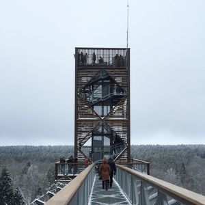 People standing on railing against sky