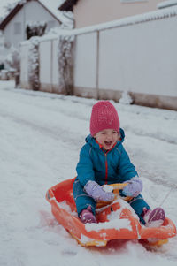 Side view of woman sitting on snow