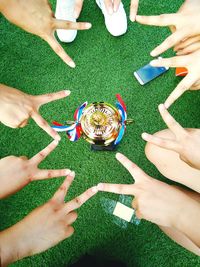 Cropped image of hands gesturing peace sign around trophy