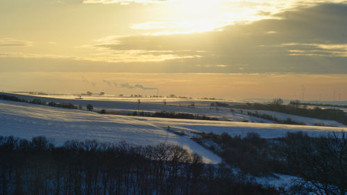 Scenic view of snow covered landscape against sky during sunset