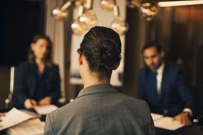 Rear view of female lawyer with colleagues in meeting at legal office