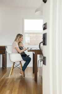 Full length side view of woman with daughter using laptop at home