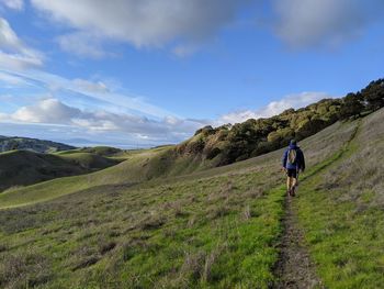 Rear view of man walking on trail against sky