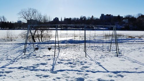 Snow covered field by trees against sky