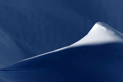 Close-up of snowcapped mountain against blue sky