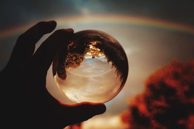 Close-up of human hand holding crystal ball during sunset