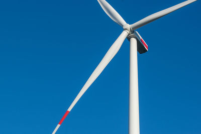 Low angle view of wind turbine against blue sky