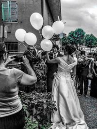 People with balloons in front of building