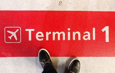 Low section of person standing on red arrow sign