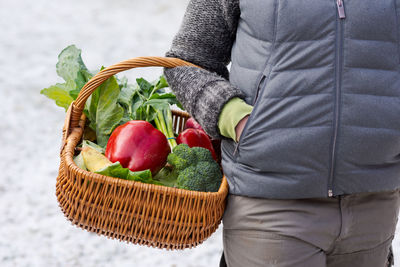 Midsection of person holding strawberries in basket