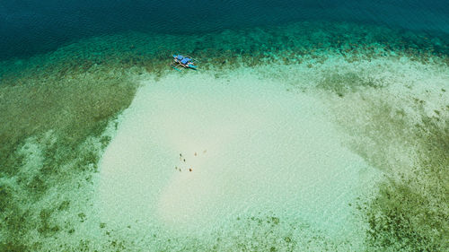 Sandy beach with tourists on a coral atoll in turquoise water, from above. balabac, palawan