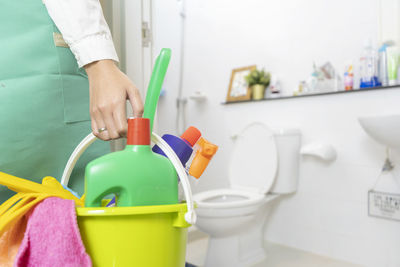 Woman holding bucket with cleaning equipments in bathroom