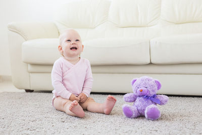 Cute baby girl sitting on sofa at home