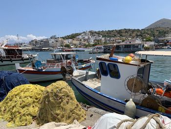 Fishing boats moored at harbor against clear sky