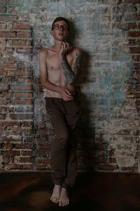 Portrait of young man standing against brick wall