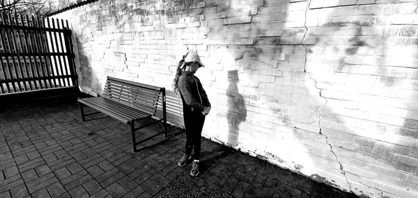 Man walking on footpath against wall