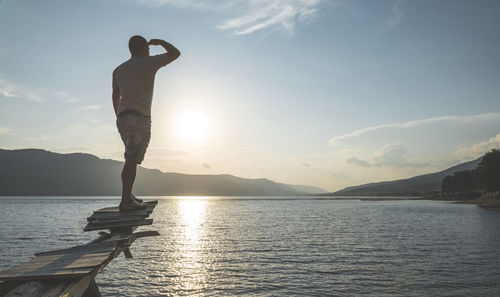 Man standing on built structure over sea against sky