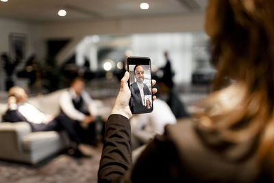 Female executive discussing through video conference with male professional on smart phone at office