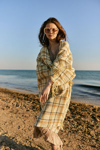 Young woman standing at beach against clear sky