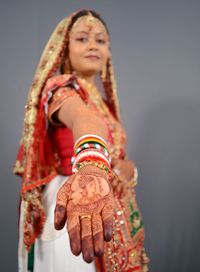 Bride showing hand with henna tattoo over gray background