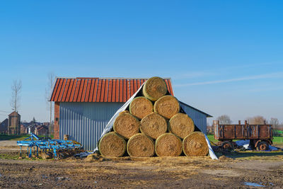 Stack of stones on field against clear blue sky