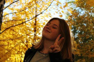 Low angle portrait of young woman against trees