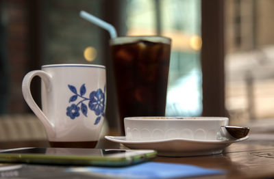 Close-up of drinks with creme brulee and mobile phone on table