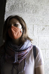 Portrait of woman covering face against wall