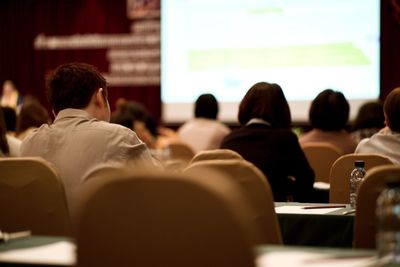 Rear view of people sitting on seat in conference