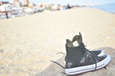 Close-up of shoes on sand at beach