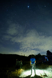 Rear view of men on field against sky at night