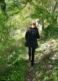 Rear view of person wearing black walking in forest 