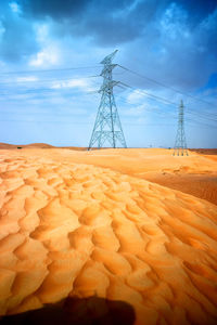 Electricity pylon on field against sky