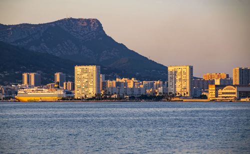 Sea by city against sky during sunset