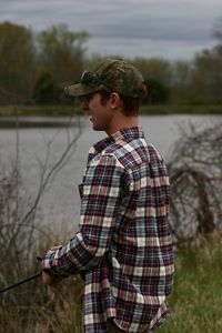 Side view of young man standing by lake